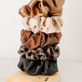 Stack of patterned scrunchies on a wooden block with a plain background