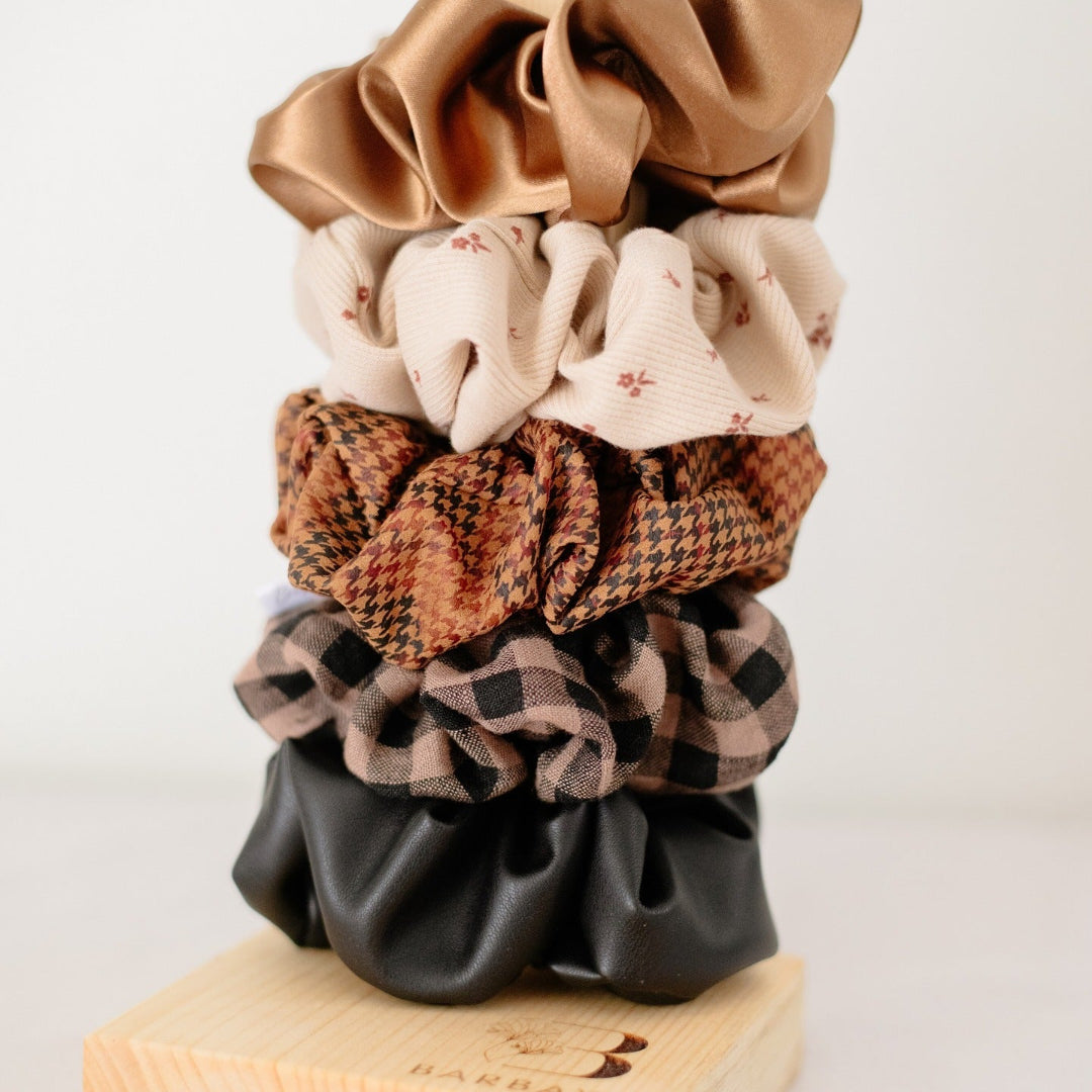 Stack of patterned scrunchies on a wooden block with a plain background