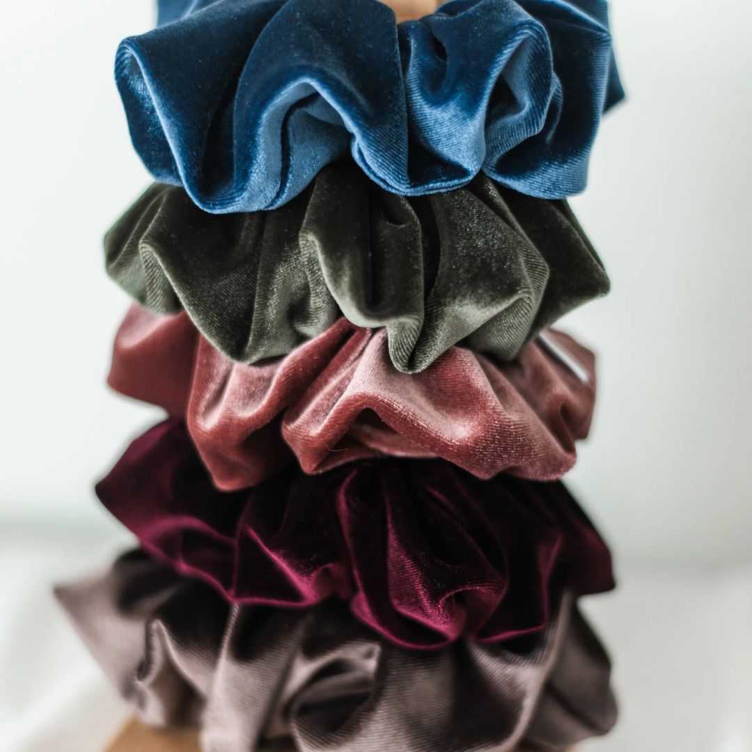 Stack of colorful velvet scrunchies on a white background