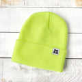 Neon green beanie with a small label on a light wooden surface