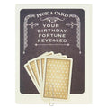 A dark grey greeting card with a white decorative border at the top and bottom. The top of the card reads "PICK A CARD" and "YOUR BIRTHDAY FORTUNE REVEALED." Below this, five fan-arranged cards with a gold and white patterned back are held by a paperclip. A second image displays five individual fortune cards, each resembling a playing card with suit symbols and text. The fortunes include messages like "YOUR LUCK IS ABOUT TO CHANGE," "SOME SECRETS ARE BEST KEPT SECRET. SORRY," and "THERE IS HIDDEN MONEY IN A
