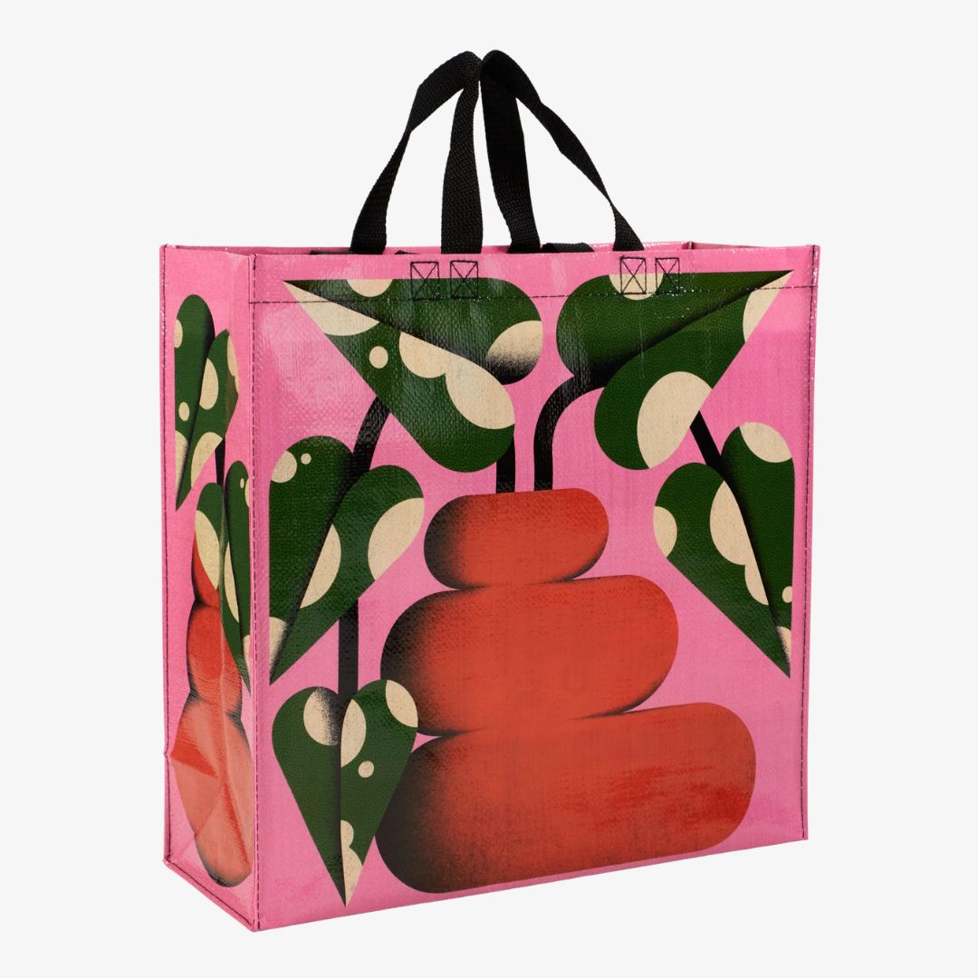 A pink reusable tote bag with black handles. The front of the bag features a large red and orange bubble-shaped vase with green leaves extending upwards and to the sides.