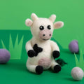 Toy cow with black spots on a green background