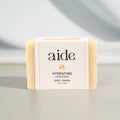 Bar of soap with 'aide' branding on a neutral background