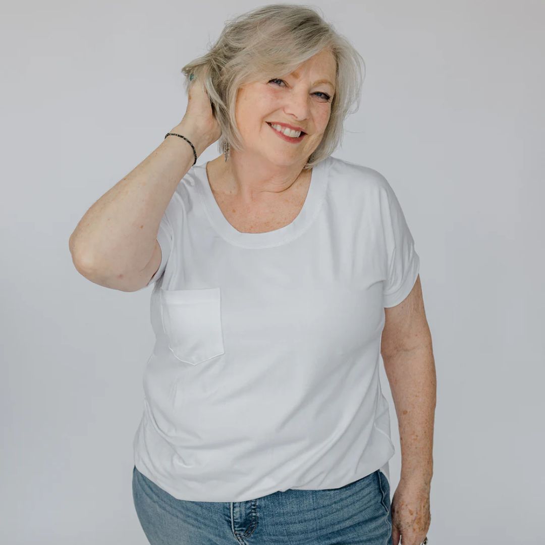 Woman wearing a white t-shirt and blue jeans against a plain background