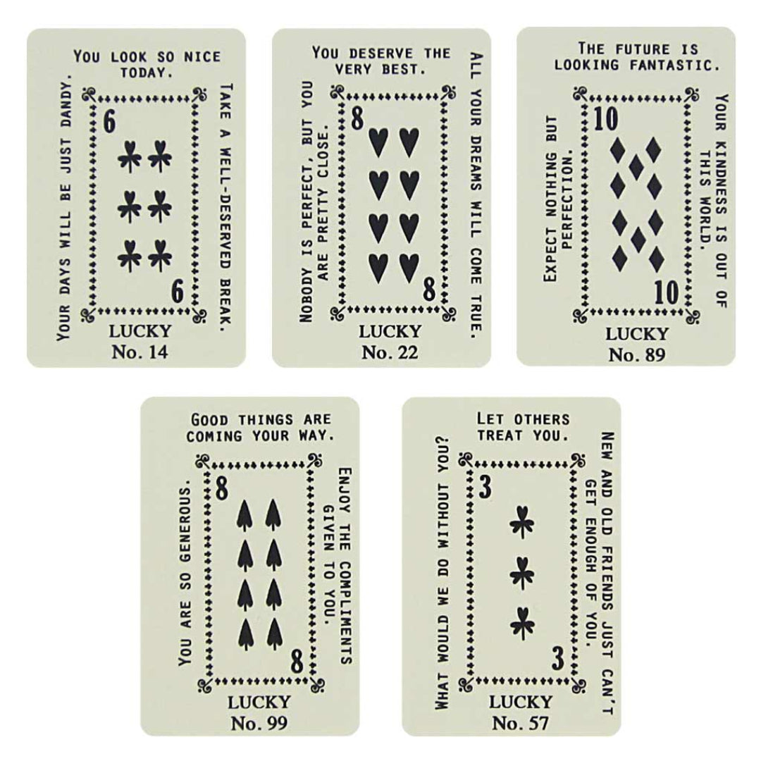 A dark grey card with white decorative borders. The top text reads "PICK A CARD" and below it, "YOUR KINDNESS WILL BE REWARDED, A POSITIVE OUTLOOK FORESEEN". At the bottom, five light green and white playing card-like fortunes are fanned out and held by a paperclip.