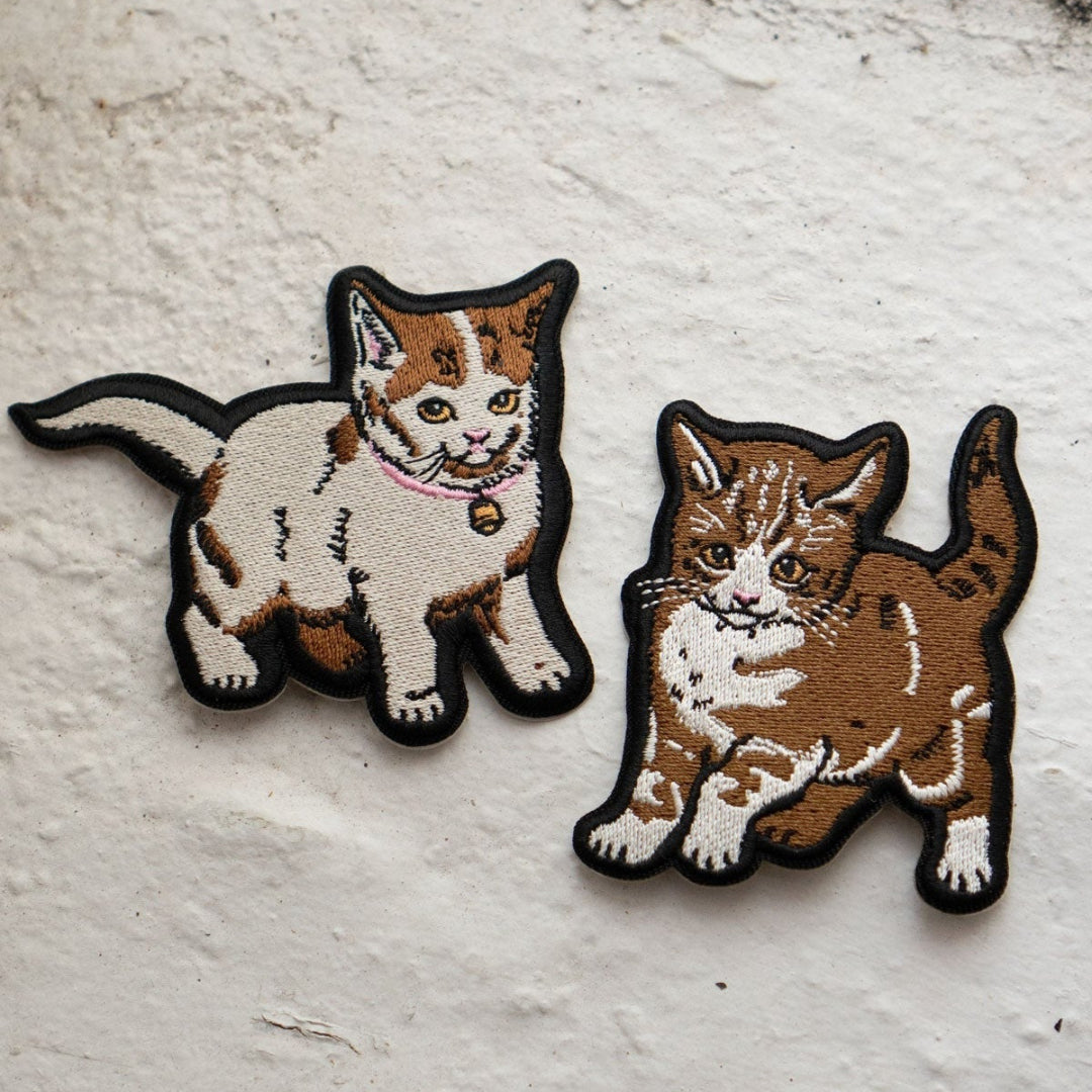 Two cat-shaped patches on a textured white surface