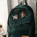 Green backpack with cat-themed patches on a white surface.