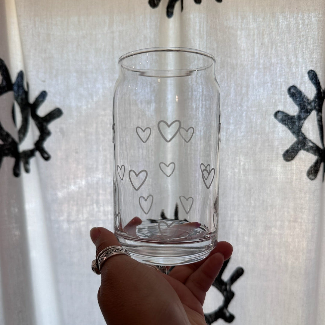 Clear glass with heart patterns held in front of a decorative background