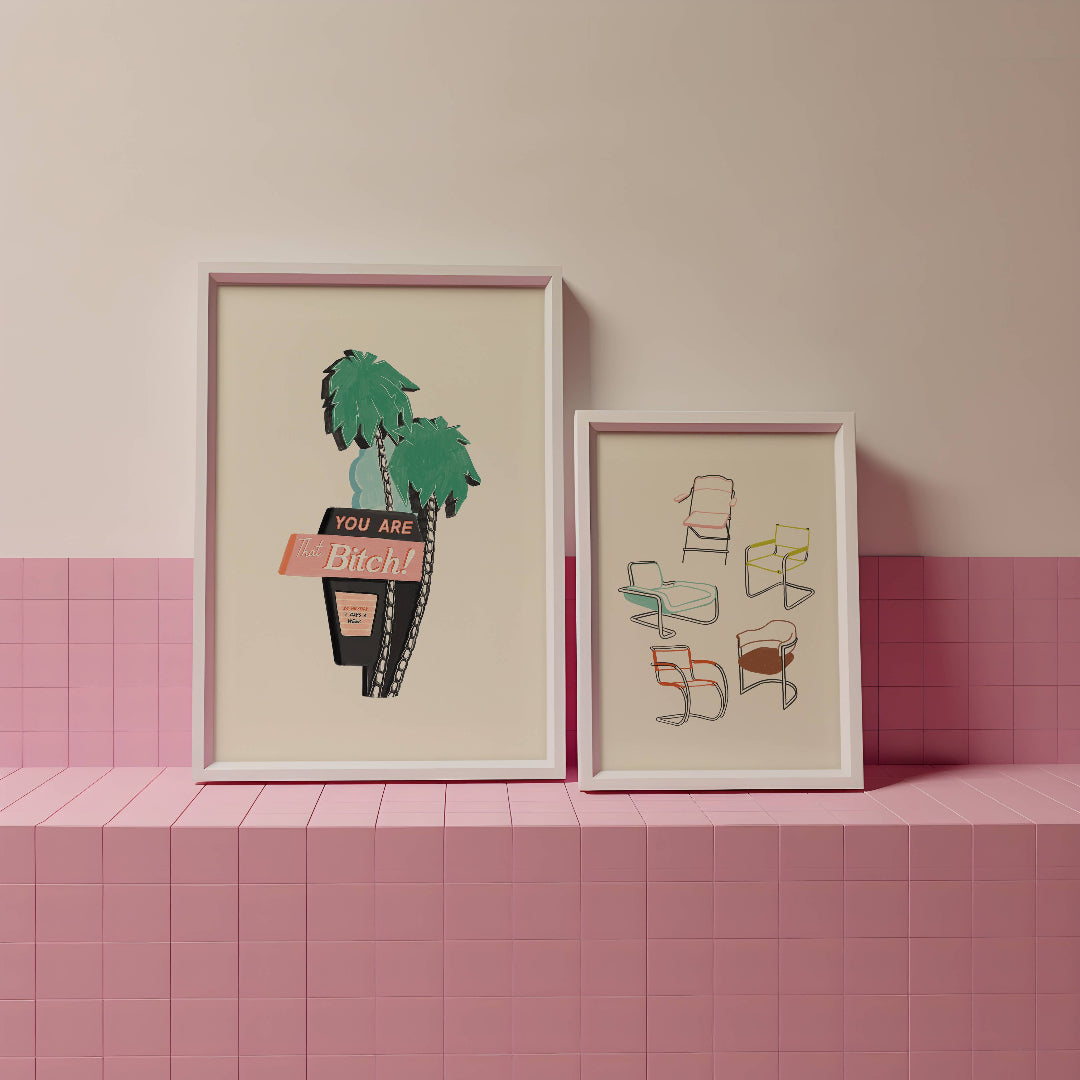 Two framed artworks on a pink tiled shelf against a pink wall.