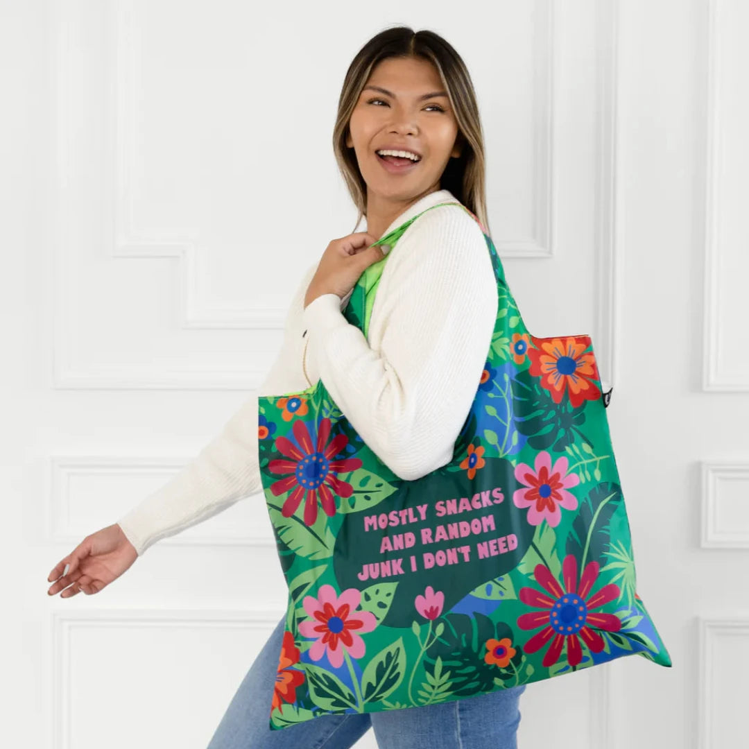 A green tote bag with a floral pattern. The text "Mostly Snacks and Random Junk I Don't Need" is printed on the bag.