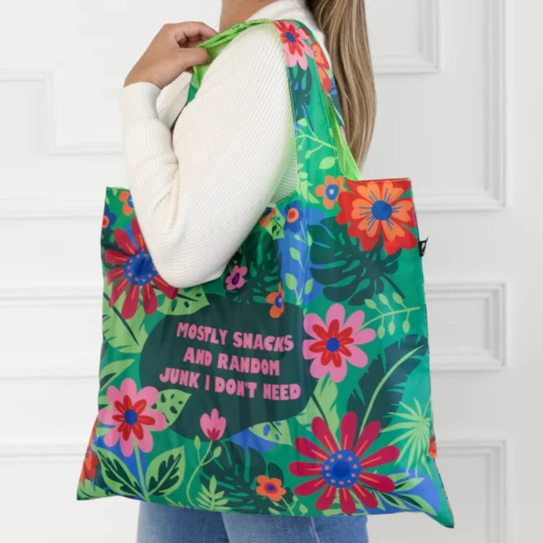 A green tote bag with a floral pattern. The text "Mostly Snacks and Random Junk I Don't Need" is printed on the bag.