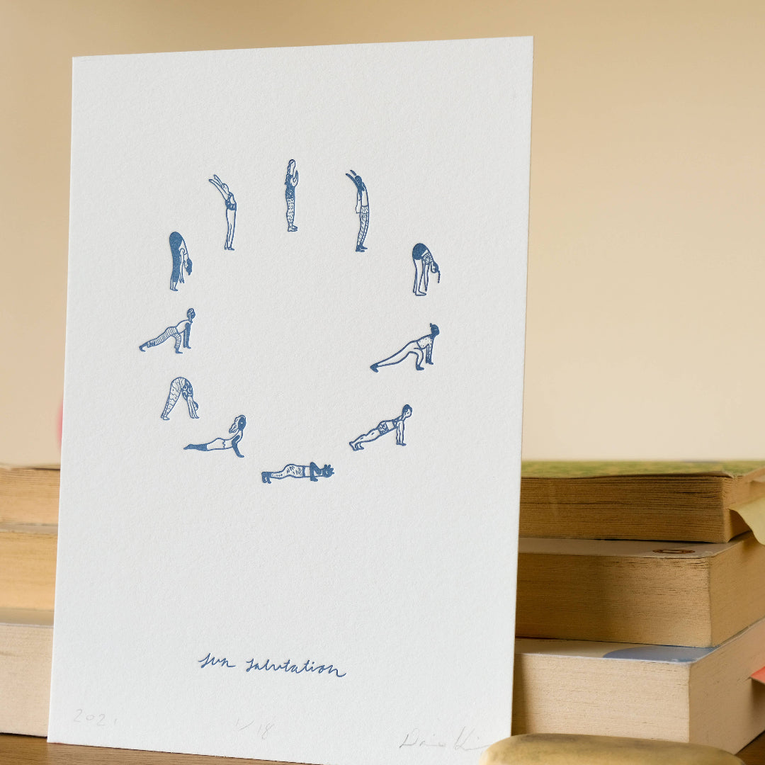 Sheet of paper with blue yoga pose illustrations on a beige background