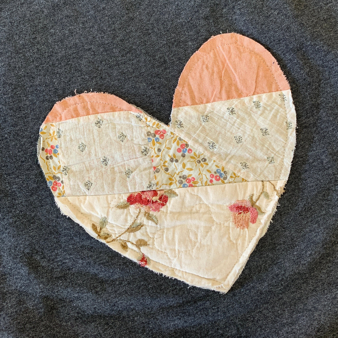 Dark gray sweatshirt with a heart-shaped patch featuring floral patterns on a plain background