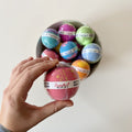 A woman holding a pink bath bomb